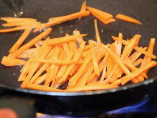 6、韩式五花肉拌饭,锅中放入适量油,放入胡萝卜丝翻炒,熟后捞出。