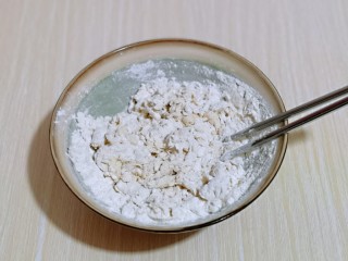 3、披萨新吃法～奥尔良鸡丁披萨,分次加入温水，一边加温水，一边用筷子搅拌成絮状。