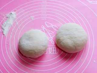 14、披萨新吃法～奥尔良鸡丁披萨,发酵好的面团取出，分成2份，盖上湿布揉圆醒发10分钟。