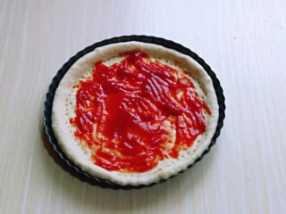 15、披萨新吃法～奥尔良鸡丁披萨,取一块面团擀成与披萨盘一样大的披萨皮，再用叉出洞洞，涂抹上番茄酱。