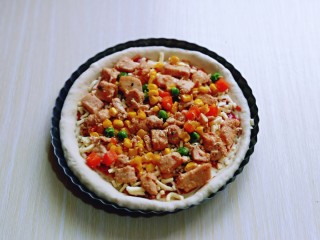 17、披萨新吃法～奥尔良鸡丁披萨,再把做好的奥尔良鸡肉均匀的铺在披萨皮上面。