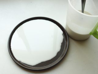 6、凉皮,找一个不沾的平盘，我用了披萨盘，舀入适量面糊，转动盘子使面糊铺满盘子。