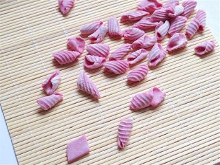 7、彩色贝壳意面,将每个小面片放在寿司帘上，然后用大拇指向前推，即可卷出好看的螺旋形状