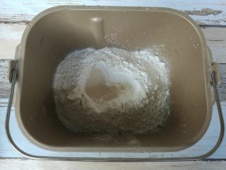 1、时蔬披萨,面包机取下桶，放在电子秤上，清零。中筋粉、水、酵母、糖、玉米油、盐、披萨草放入面包机。启动面包机发面程序。（没有面包机手揉也可以）