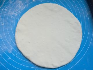 4、时蔬披萨,烤箱上下火200度预热10分钟。发酵好的面团取出排气擀成圆饼。