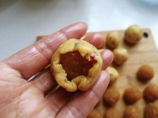 20、玫瑰凤梨酥,再取一份凤梨内馅放入面皮中，用虎口向上收拢捏紧，然后像包月饼一样把面皮向上推挤包好滚圆