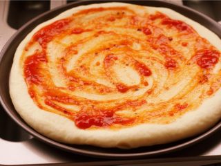 10、培根玉米粒披萨,取出烤好的饼皮，均匀的涂抹一层披萨酱。