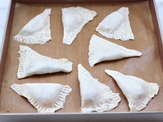 8、酥皮紫薯肉松派,把面皮移步到烤盘上，铺上油纸，把面皮对折一下后，用叉子按压边边。