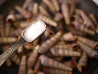 3、麻辣田螺,锅中加入1勺盐调味。