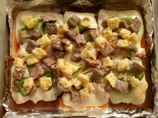 11、吐司披萨,把已经烤了5分钟的吐司披萨从烤箱取出，把吐司碎铺在上面。