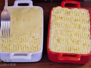 11、牧羊人派,把土豆泥分布在肉酱上面，用刮刀抹平，用叉子划出花纹，撒上奶酪丝