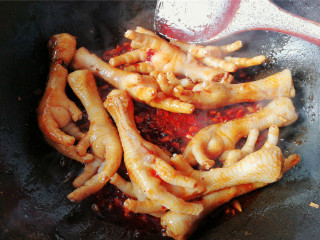 11、酸甜辣酱鸡爪,把调制好料汁倒入翻炒，让鸡爪混合均匀