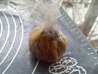 8、五仁月饼,把保鲜膜提起,捏紧,两面慢慢向上推均匀,直到把馅完全包住。