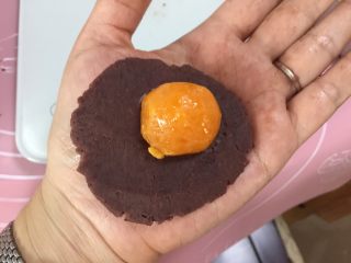11、广式蛋黄红豆沙月饼,然后将红豆沙按扁，中间厚边缘薄，放入咸蛋黄