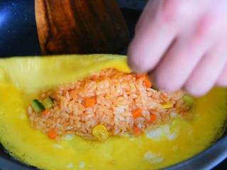 4、简易蛋包饭—黄金满兜的好运蛋包饭，你必须了解一下,铺上米饭，鸡蛋饼对折，压实调中火，再煎一下即可出锅。