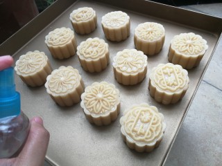 11、广式莲蓉蛋黄月饼,在烤盘上印出月饼花纹，依次做好12个，然后用小喷雾壶喷少许水在月饼表面准备进炉烘烤