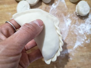 15、韭菜盒子,对折将边缘捏紧,捏出花边。