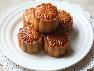 15、广式椰蓉月饼,在月饼表面喷点水，放入200度预热烤箱，烤5分钟左右，月饼表面花纹定型后，取出，在表面刷上蛋黄液；继续入烤箱，烘烤15分钟左右，饼皮均匀上色即可