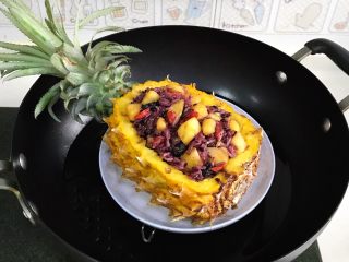 12、香甜菠萝糯米饭,把拌好的糯米饭填入菠萝壳中,然后把菠萝糯米饭放入锅中。这里建议大家把菠萝绿色叶子部分切掉,特别是长的叶子,锅小的话就盖不住了。