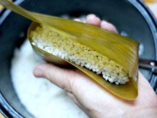 2、蜜枣白米甜粽,剩下2/3的粽叶往上折叠，盖住糯米。
