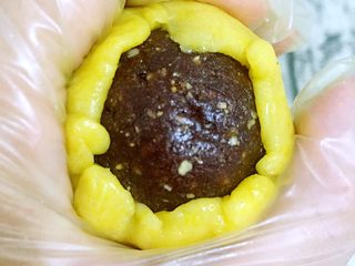 11、韩式南瓜????小月饼,将压扁的面团紧紧包裹住豆沙坚果球，最好做到均匀不露馅，方法基本同蛋黄酥制作方法一致，如果感到面团粘手，可以用少许玉米淀粉做手粉，就会很方便操作，注意是手粉不要粘太多，防止皮馅分离。