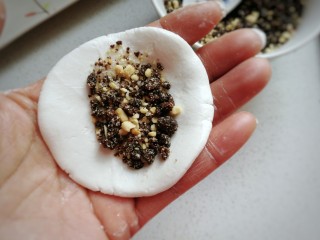 6、红糖炒汤圆,取一份圆面团用手压扁，放上适量馅料；