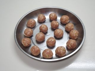5、照烧小丸子,用手将肉馅挤成丸子摆放在盘上。