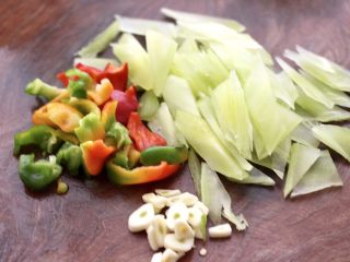 2、桃花蛸爆莴苣,莴苣去皮后，用刀切成菱形薄片，彩椒切片，大蒜切薄片。