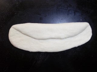 12、原味贝果（超详细版）,将其翻面，与身体平行的横放在操作台上 ，自三分之一处内折，用手掌根部拍紧，防止有空气。