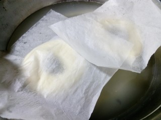 20、原味贝果（超详细版）,将发酵好的面团取出，用手托着连油纸一起放进糖水，油纸自然会掉落。(因为贝果底部可能会粘，如果直操拽下来，会导致变形，而且面团易塌掉，这也就是一定要放在油纸上的原因。)