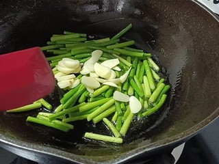 12、蒜苔炒腊肠,倒入蒜片。