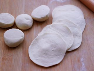 12、小苔菜虾皮花样包子,把剂子摁扁后,用擀面杖擀成圆形薄面皮。