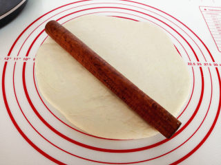 5、海陆至尊披萨,把面团发在揉面垫上，如果沾可以适量撒些干面粉，擀成比模具略小的圆盘，