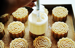 16、白莲蛋黄月饼,将带着月饼的模具放在烤盘上，轻微下压模具，推出月饼落在烤盘上。