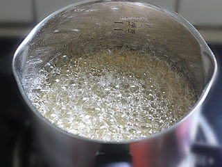 5、转化糖浆,再度煮开以后，转小火，慢慢熬煮。从这个时候一直到煮糖浆结束，切记都不要再搅拌糖水。如见锅的边缘有可能一部分糖水粘在了锅壁上。为了防止这部分糖产生糖晶颗粒，可以拿一个毛刷沾水，在锅壁上刷一圈。水沿着锅壁流下去的时候可以将锅壁上的糖洗刷到锅里去