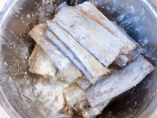 8、柠檬草椰汁轻烧带鱼,将大概20g的淀粉和40g的面粉混合,然后撒到盆里,翻滚刀鱼,让每一条鱼的每一面都沾上一层干粉。标准是基本看不到鱼本来的皮肤,也不要太厚,一层包裹就可以。一点一点撒,粉不够,就再撒一些。