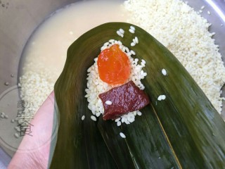 6、咸蛋肉粽子,卷的时候一边长的，不是一样平的，卷好如图，放一点糯米，然后放馅料