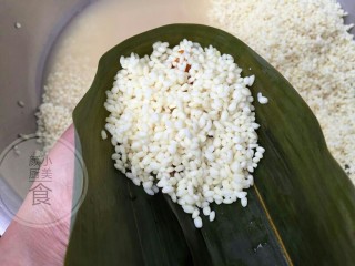 7、咸蛋肉粽子,再加满糯米，拿着粽叶往盆边轻轻敲打，就是让糯米比较实，包出来的粽子结实好吃，不会是松散的。