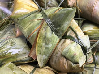 8、咸蛋肉粽子,粽叶往前面折起来，用粽绳在粽子中间捆绑起来，要绑的紧一点，这样煮出来粽子才不会散开。