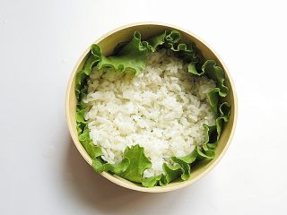 10、兔子趣味便当,消毒过的便当盒用生菜叶铺好，放入少量米饭摊开铺好