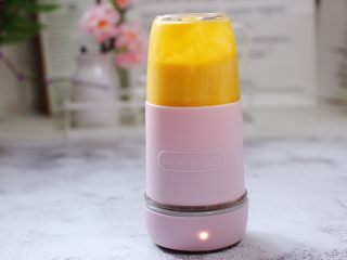 11、芒果苹果奶昔,把果汁杯倒放在桌面上,按启动键,打成奶昔即可。