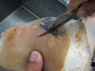 3、红烧肘子,刮刀刮去表皮焦糊的地方，清水冲洗干净。