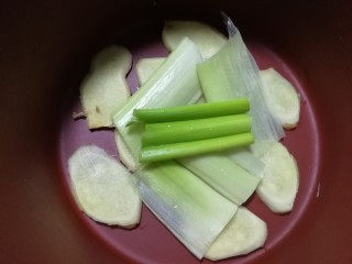 8、红烧肘子,炖锅里铺上姜片和葱段。