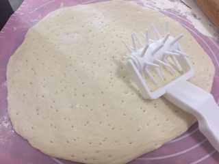 20、海陆双拼披萨,在案板上撒了面粉，取出面团擀圆，然后用滚针在面皮上滚一滚