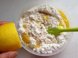 3、玉米油版酥性饼干,蛋液和玉米油加入面粉中先翻拌几下，再挤入适量柠檬汁翻拌均匀