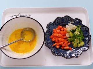 2、补钙又营养的虾仁豆芽蛋炒饭,用刀把蒜苗切碎,胡萝卜切丁、鸡蛋打散备用。