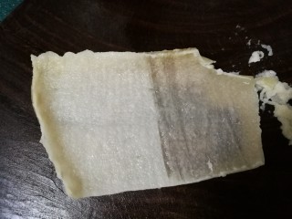 2、豆皮猪皮冻,将煮好的肉皮平铺在菜板上，里层有油脂的一面朝上，用刀反复刮去上面的油脂。要想皮冻清爽不腻，这是关键一步，必须把油脂仔细刮干净。