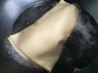 11、豆皮猪皮冻,在肉皮汤冷却的功夫，将豆腐皮整张放入锅里清水煮两分钟。注意别煮破了。