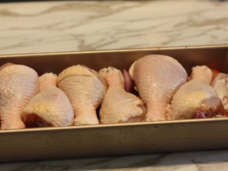 3、【蒜香番茄烤鸡腿】,把鸡腿放在番茄和洋葱上