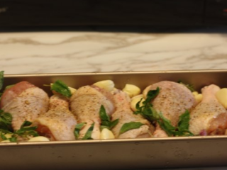 6、【蒜香番茄烤鸡腿】,把2个大大的蒜,蒜剥皮,放在鸡腿四周,再在鸡腿表面放些罗勒叶